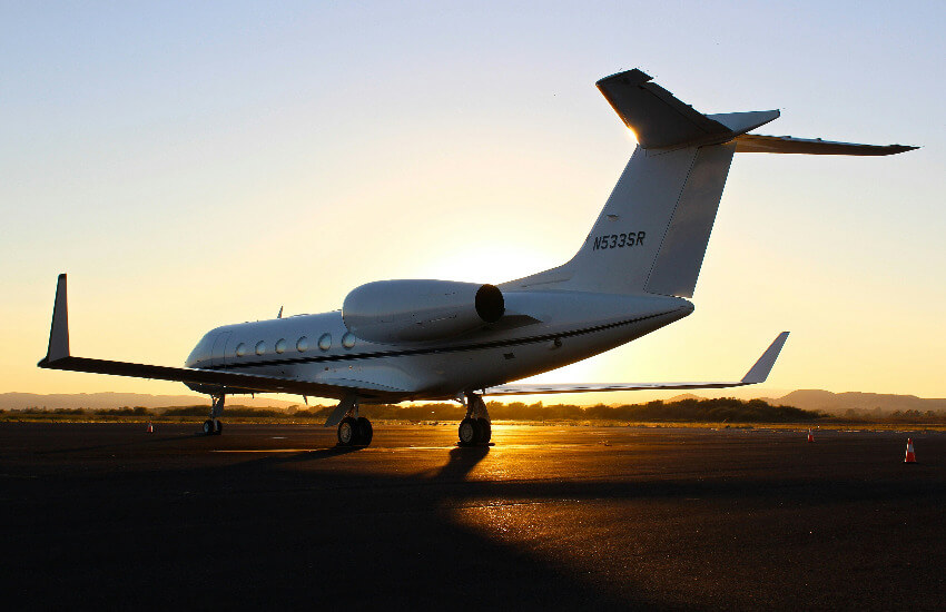 Ein Privatjet parkt am Flughafen während eines Sonnenuntergangs.